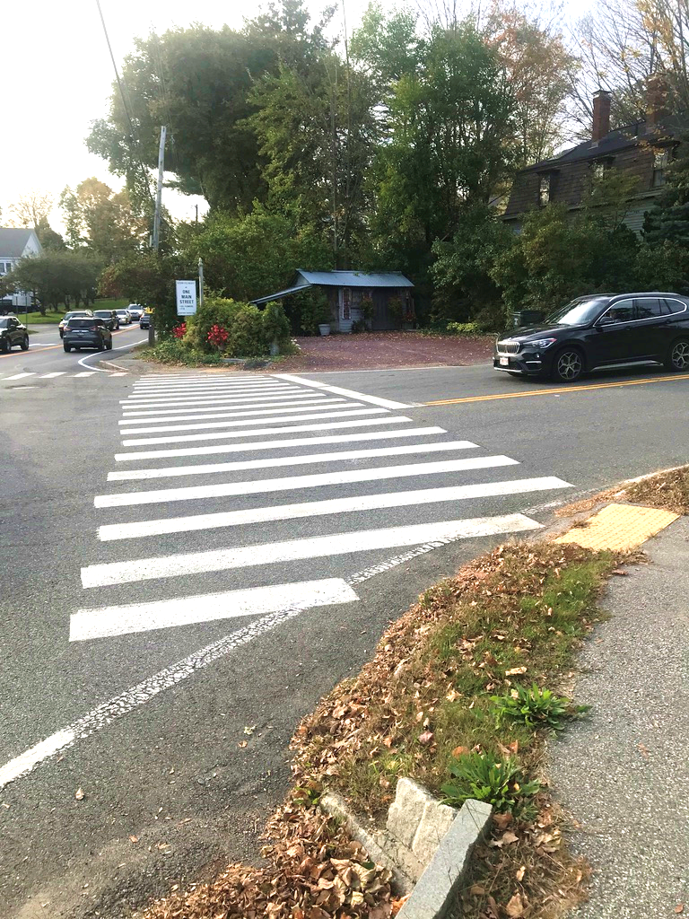 Figure 5 - Pedestrian Facilities for Northeast Intersection Corner’s Library Hill Road Crossing. Image shows a pedestrian detectable warning strip, a sidewalk made of pavement, and a crosswalk. Figure 5 - Pedestrian Facilities for Northeast Intersection Corner’s Library Hill Road Crossing. Image shows a pedestrian detectable warning strip, a sidewalk made of pavement, and a crosswalk.